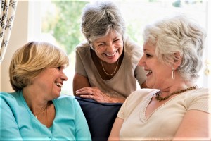Three women in living room talking and smiling